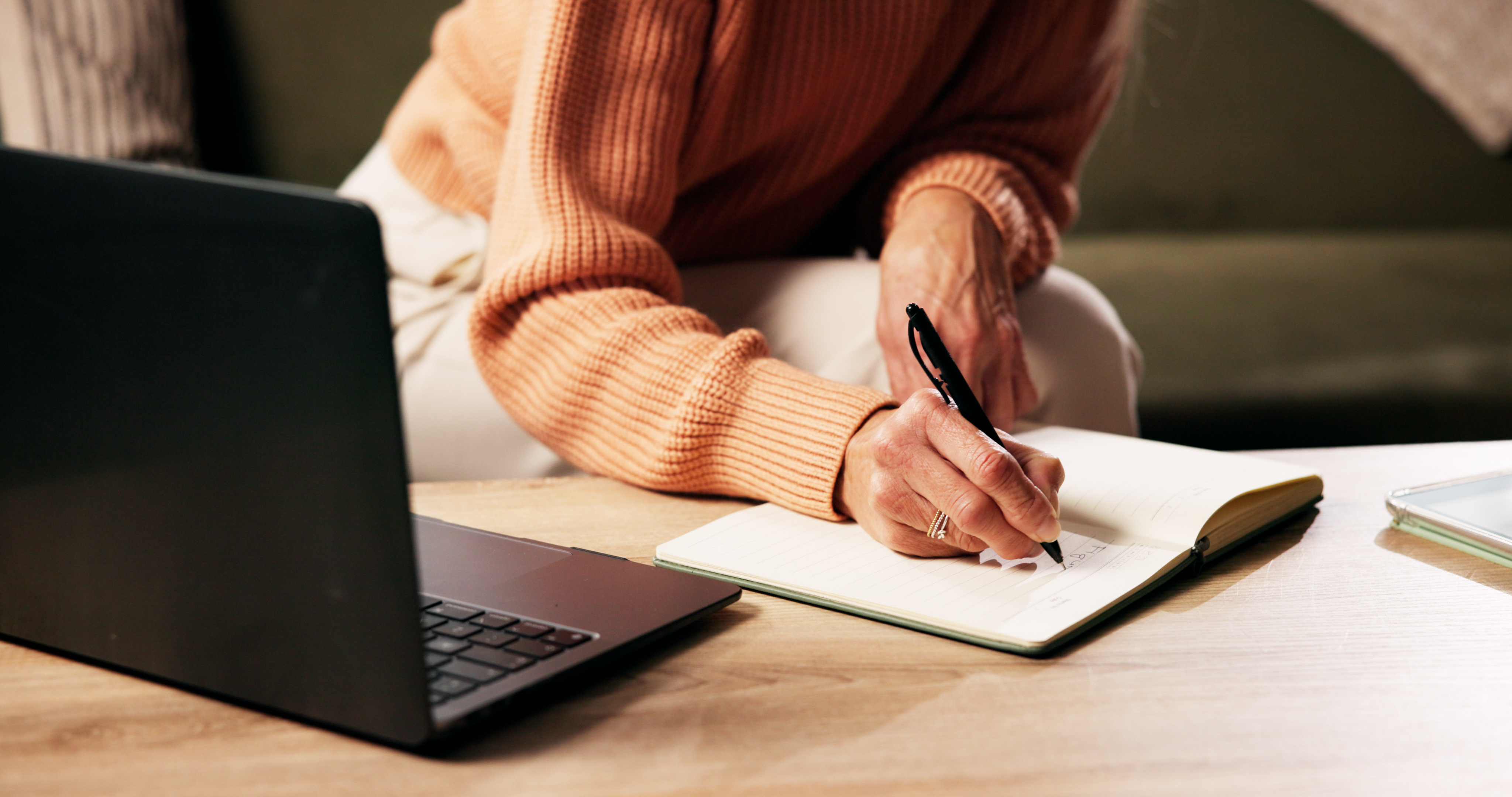 Seniorin notiert Lernziele in ihr Tagebuch am Schreibtisch